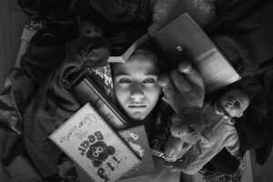 A girl lying on the ground with a pile of rubbish and clutter around her face