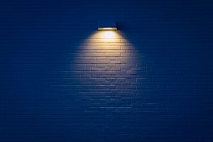 A black and dark tiles wall with one light 